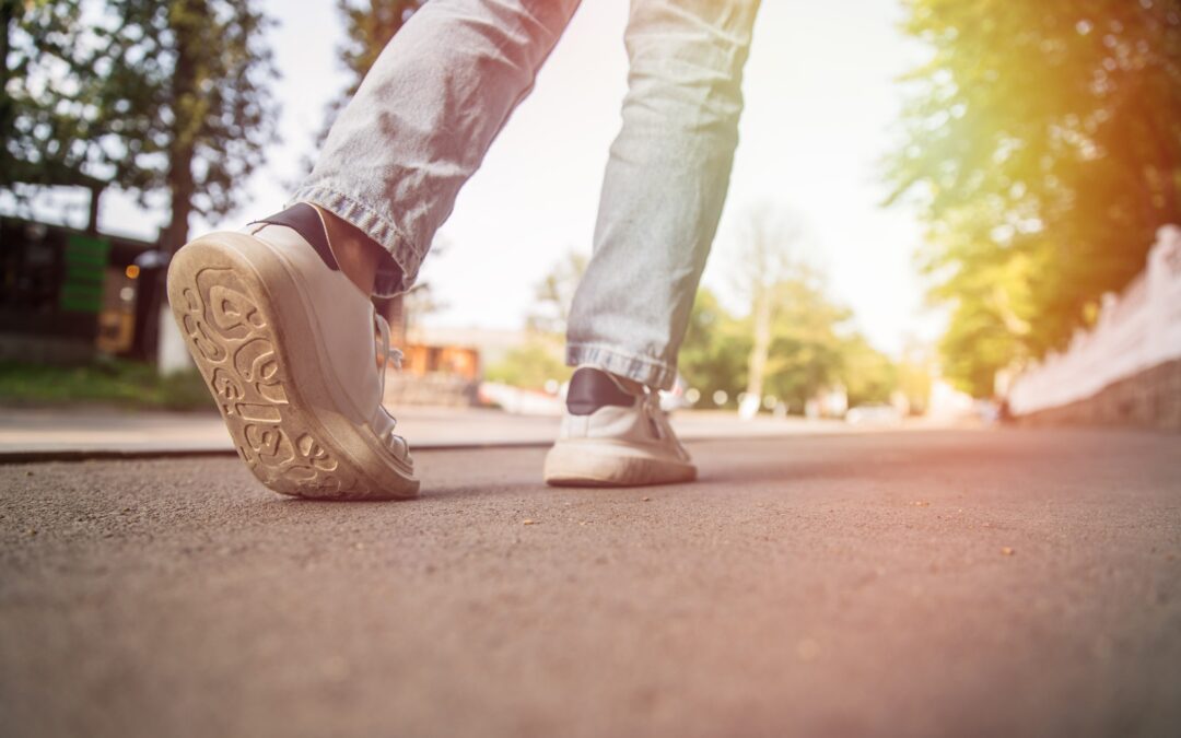A person walks away on a paved road wearing jeans and sneakers. Walk a Mile in My Shoes is about empathy.