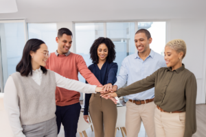 A group of smiling people with all their hands in the middle.