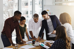 A group of people standing around a table, working together.